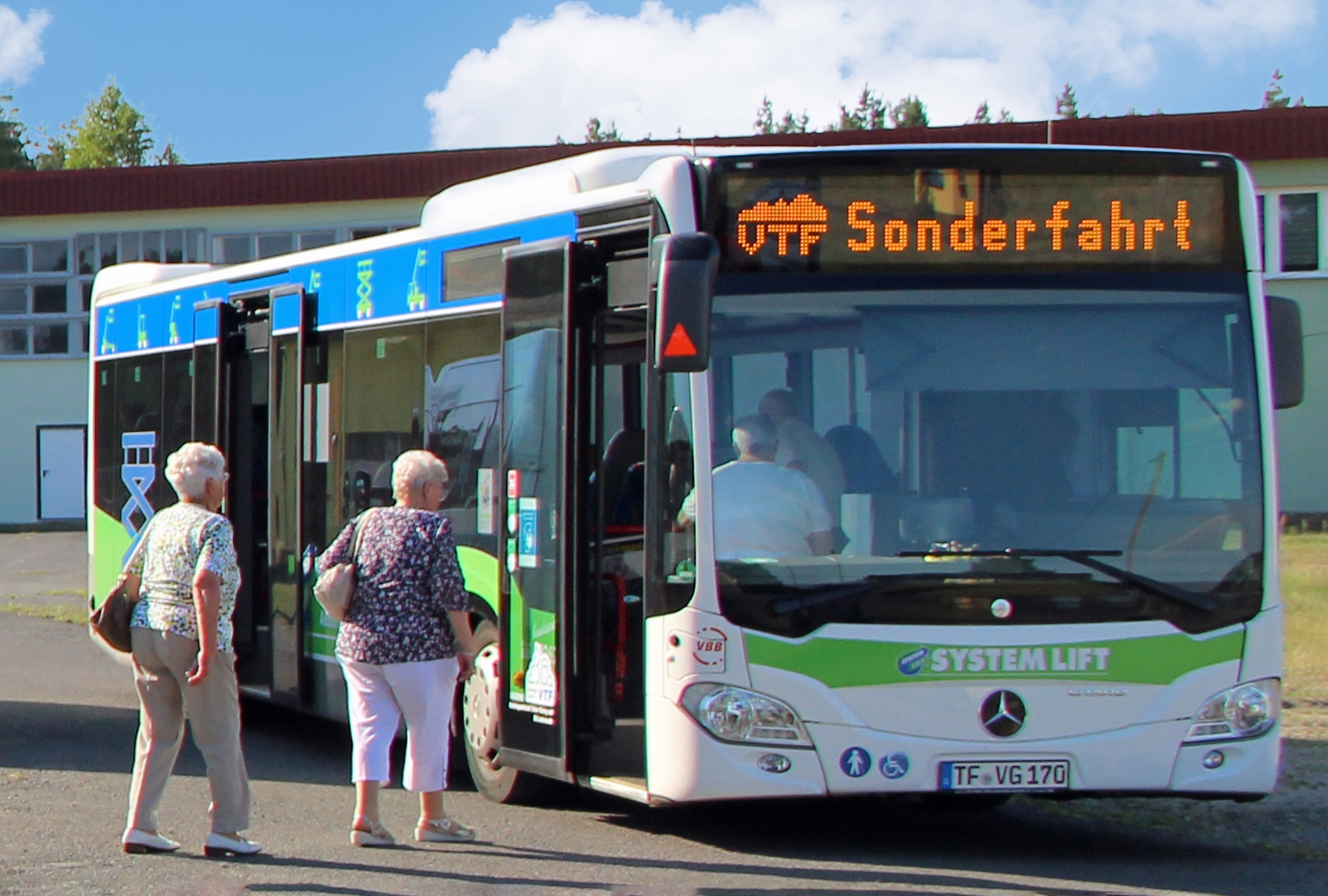 Ältere Personen steigen in einen weiß-blauen Bus ein. Auf der Anzeige ist "Sonderfahrt" zu lesen.