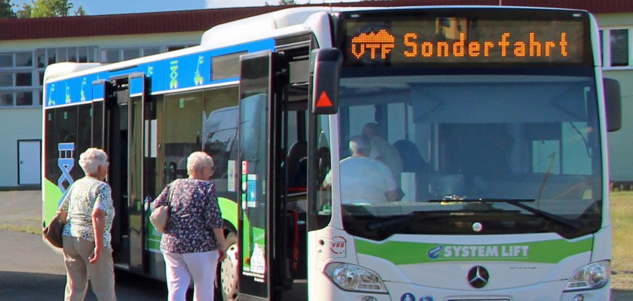 Ältere Personen steigen in einen weiß-blauen Bus ein. Auf der Anzeige ist "Sonderfahrt" zu lesen.