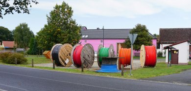 Glasfaserausbau Kabeltrommeln mit verschiedenfarbigen Leerrohren für Glasfaserkabel stehen auf einem Dorfplatz