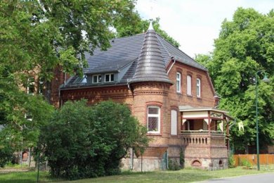 Backsteingebäude mit Turm, umgeben von Bäumen