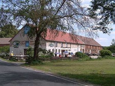 Café "Die Scheune" Großes Scheunengebäude mit Bäumen und Wiese davor