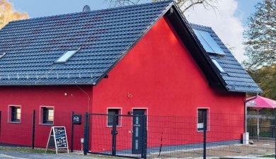 rotes Gebäude an einer Straße mit Bäumen im Hintergrund