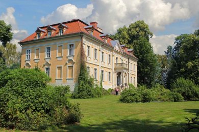 Schloss Stülpe ein Schloss, umgeben von grünem Rasen, Sträuchern und Bäumen