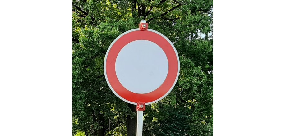 Verkehrszeichen: Durchfahrtsverbot für Fahrzeuge aller Art rundes Verkehrszeichen, innen weiß mit rotem Rand außen, vor grünen Bäumen